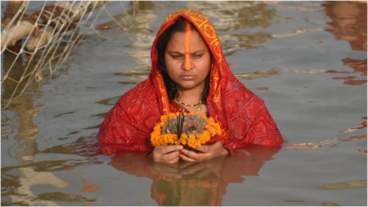 a lady offering arghya to morning sun during chhath puja 